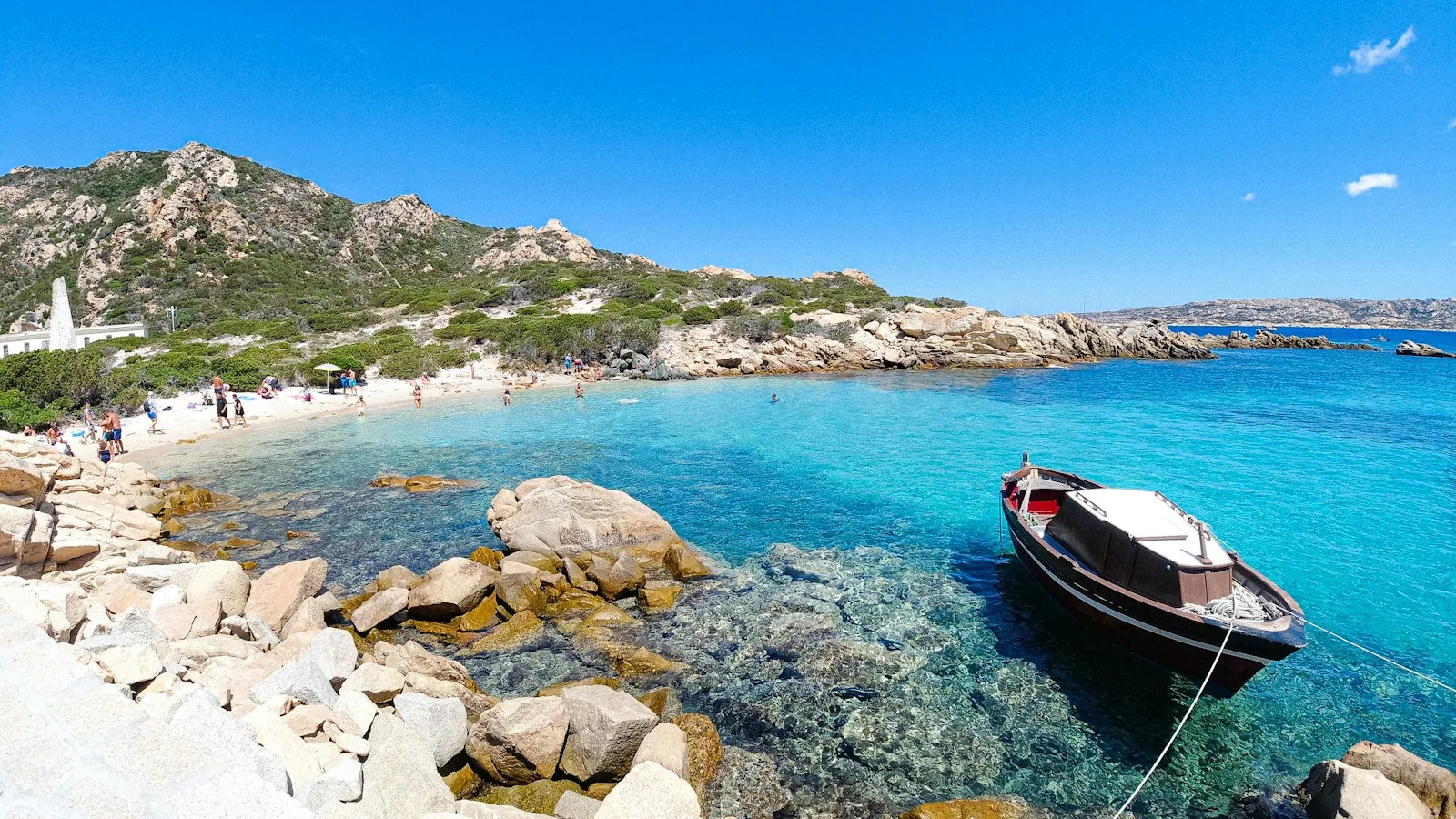Bateau d'excursion mouillant dans une eau turquoise de l'archipel de La Maddalena en Sardaigne
